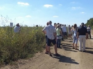 Several people are standing in a field trial and on the path next to it